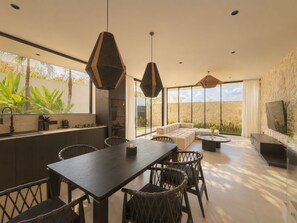 A modern kitchen with a dining area, large windows, and a stone wall.
