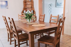 Une table de salle à manger en bois, ornée d’un vase de fleurs et de sets de table, entourée de chaises en bois.