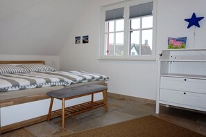 A bedroom with a bed, bench, window, and a white dresser. - Thatched house "De Leevde" (Zierow)