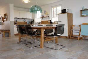 A modern kitchen with a dining table, chairs, and a pendant light. - Thatched house "De Leevde" (Zierow)