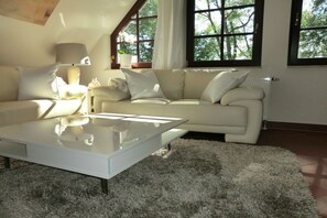 A modern living room with a white sofa, a glass coffee table, and a fluffy rug. - Buoy in the house Sanddorn (Ahrenshoop)