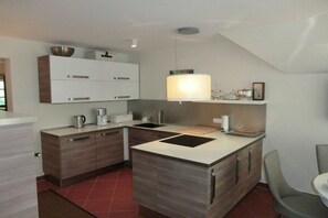 A modern kitchen with a central island, built-in cabinets, and a hanging light fixture. - Buoy in the house Sanddorn (Ahrenshoop)