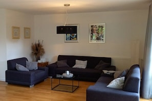 A modern living room with a dark-colored sofa set, a coffee table, and framed artwork on the walls. - Holiday home with 4 bedrooms (Ahrenshoop)