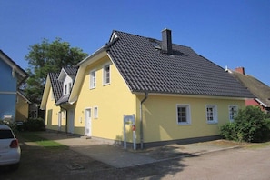 A yellow building with a sloped roof, a door, and a small window. - Holiday home with 4 bedrooms (Ahrenshoop)