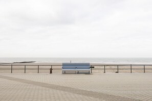 A paved walkway with a bench and a railing overlooking a beach. - Holiday home in Middelkerke with Wi-Fi (Middelkerke)