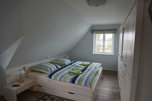 A bedroom with a single bed, a nightstand, a window with a view, and a wardrobe. - Holiday home with 1 bedroom (Born a. Darß)