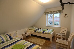 A bedroom with a single bed, a chair, a nightstand, and a window. - Holiday home with 1 bedroom (Born a. Darß)