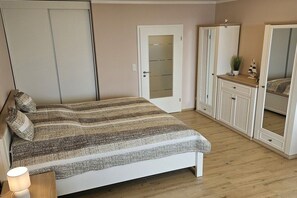 Ein Schlafzimmer mit einem Bett, einem Kleiderschrank, einem Spiegel und einem Nachttisch mit einer Lampe.