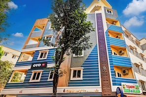 Un hotel de varios pisos con fachada azul y beige, balcones y un letrero que dice 'OYO Hotel'.