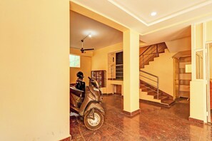 Un interior espacioso con suelo de mármol, una escalera y un ventilador de techo.