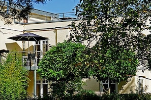 Ein Gebäude mit Balkon, Baum und blauem Himmel.