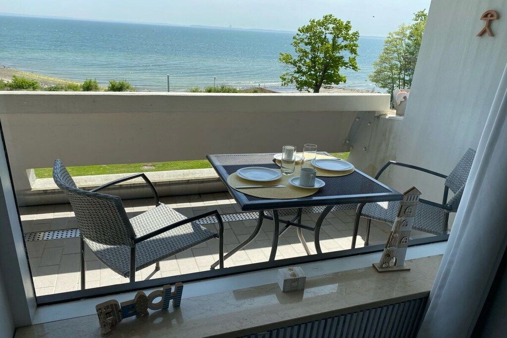 A balcony with a table set for two, overlooking a body of water.