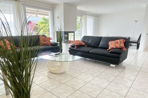 A modern living room with two black sofas, a glass coffee table, and a fireplace. - Residenza Sette Nani (San Nazzaro , Vairano)