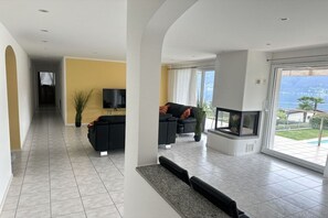Ein modernes Wohnzimmer mit Kamin, Fernseher und Blick ins Freie.