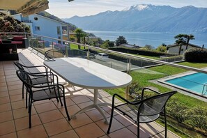 Eine Terrasse mit Tisch und Stühlen, ein Schwimmbad und Blick auf die Berge.