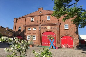 Ein Backsteinhaus mit zwei roten Türen und einer großen 'X'-Verzierung an der Fassade.