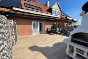 A brick house with a patio, a grill, and a stone wall. - 10 holiday apartment "Anders Fewo 1" (Burg auf Fehmarn)