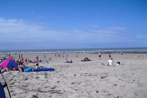 A beach with people relaxing and sunbathing, some under umbrellas. - Holiday home in Bredene with swimming pool (Bredene)