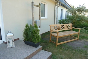 A wooden bench outside a house with a potted plant and a lantern on the steps. - Bodden view with sauna (Pruchten)