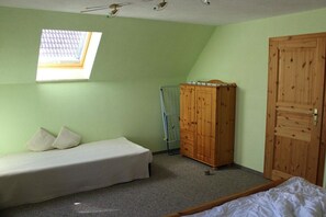 Ein kleines Zimmer mit einem Einzelbett, einem Holzschrank, einer Heizung und einem Oberlicht.