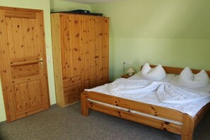 A bedroom with a wooden bed, a wardrobe, and a nightstand with a lamp. - House Elke Apartment 1st Floor (Wieck a. Darß)