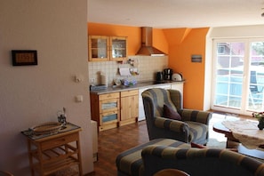 A kitchen with wooden cabinets, a coffee maker, and a window with a view of the outside. - House Elke Apartment 1st Floor (Wieck a. Darß)