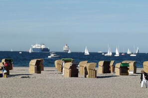 A beach with beach huts and sailboats in the background. - Holiday apartment with 1 bedroom (Travemünde)