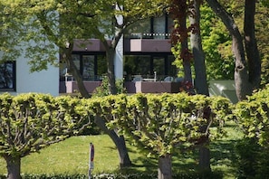 A modern building with a flat roof, large windows, and a balcony with outdoor seating. - Holiday apartment with 1 bedroom (Travemünde)