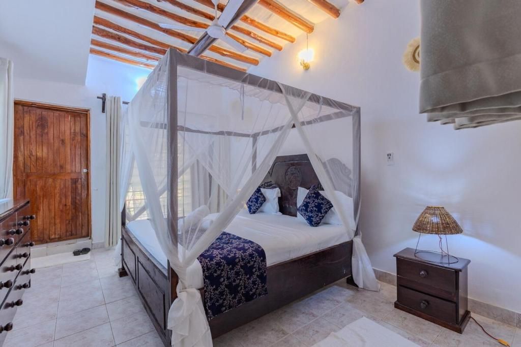 Une chambre à coucher avec un lit à baldaquin, une armoire en bois, une table de chevet et une lampe.