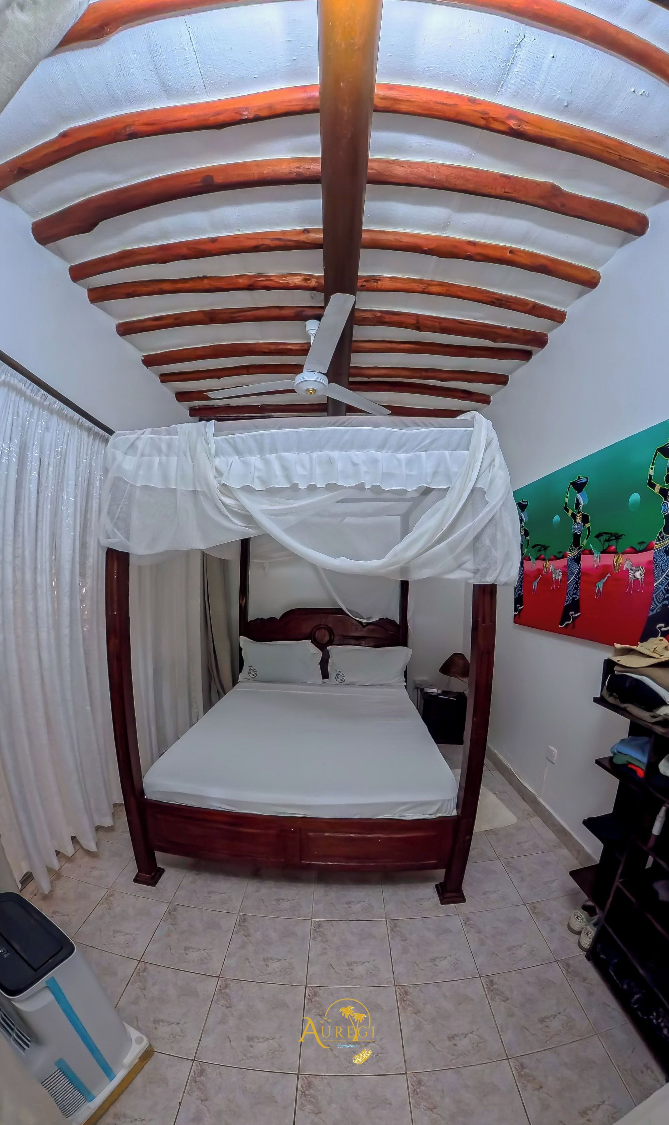 Una habitación con cama, ventilador de techo y un cuadro en la pared.
