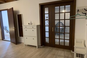 A room with a wooden door, a white dresser, and a hanging garment rack. - 12 Holiday apartment "Family Time" (Burg auf Fehmarn)