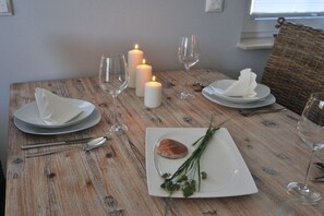 Mesa de jantar posta com pratos, talheres, copos e velas.
