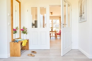 A hallway with a wooden bench, a mirror, and a door leading to a dining area. - Holiday home with 2 bedrooms (Fuhlendorf)