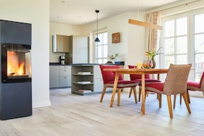 Eine moderne Küche mit integriertem Kamin, Esstisch aus Holz und roten Polstermöbeln.