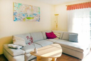 A living room with a sofa, a coffee table, a floor lamp, and a painting on the wall. - Holiday apartment with 2 bedrooms (Prerow)