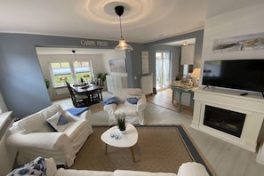 Ein Wohnzimmer mit Kamin, Fernseher und einem Essbereich mit Tisch und Stühlen.