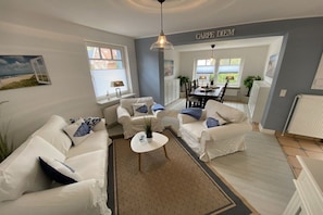A living room with a sofa set, a coffee table, and a dining area with chairs and a table. - Holiday apartment with 2 bedrooms (Travemünde)