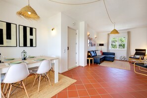 A modern living space with a dining area, a sofa, and a window with a view. - Casa da Galé Pool Terrace (Albufeira)