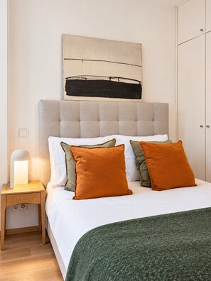 A bedroom with a bed, pillows, a bedside lamp, and a wardrobe. - Vila Rosário - 1 BR With AC Penha de França (Lisbon)