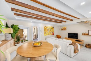 A modern living room with a round wooden table, white sofas, and a TV. - Charminn Mar (Ovar)