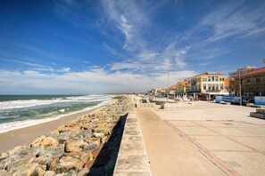 Un paseo marítimo con un muro de piedra, edificios y cielo despejado.