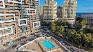 Ein hoch aufragendes Wohngebäude mit mehreren Balkonen, einem Schwimmbad und einem Parkplatz.