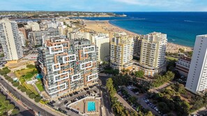 Ein Hochhaus mit Wohneinheiten, mehreren Balkonen, einem Schwimmbad und Blick auf den Strand.