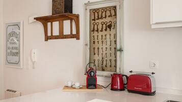 Een keuken met een houten kastje, een sleutelrek aan de muur, een vintage telefoon, een rode toaster en een waterkoker op het aanrecht.