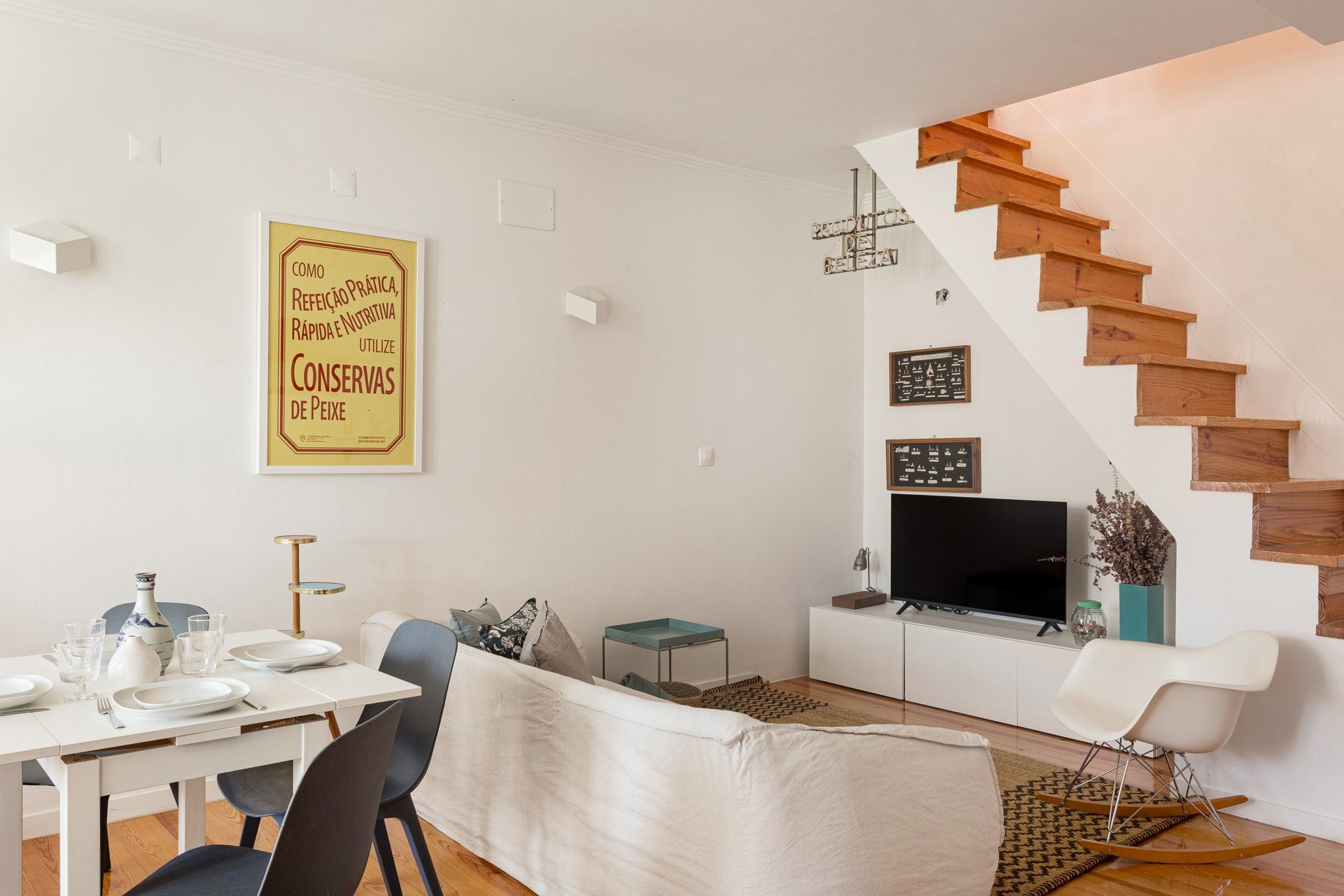 Een moderne woonkamer met een eethoek, een trap en een flatscreen-televisie.