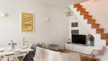 Een moderne woonkamer met een eethoek, een trap en een flatscreen-televisie.