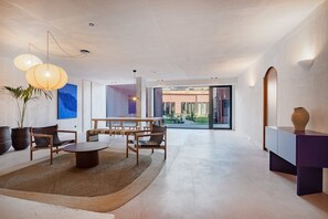 A spacious living area with a dining table, chairs, and a coffee table. There is a large window providing a view of the outside. - Skylight Loft Terracotta Collection (Porto)