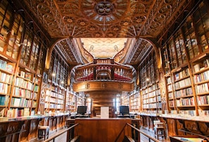 A library interior with ornate woodwork, bookshelves, and a central reading area. - Skylight Loft Terracotta Collection (Porto)