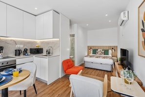 A compact hotel room with a kitchenette, a bed, a seating area, and a TV. - Porto Garden Private Patio Studio (Porto)