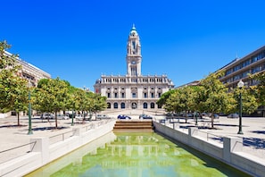 A historic building with a prominent clock tower, a central fountain, and a symmetrical layout with trees and seating areas. - Porto Garden Private Patio Studio (Porto)